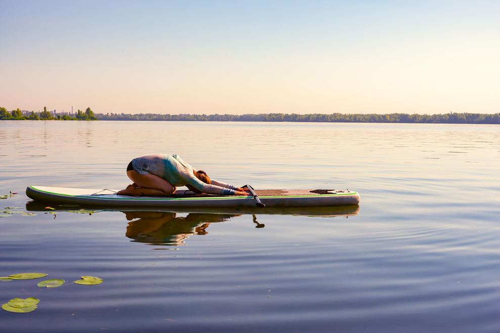 Woman is practicing yoga on a SUP board