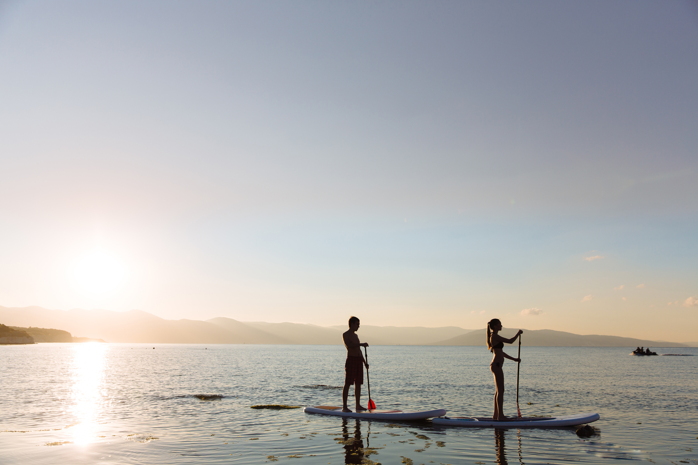 Silhouette of male and female on sup surf swimming at